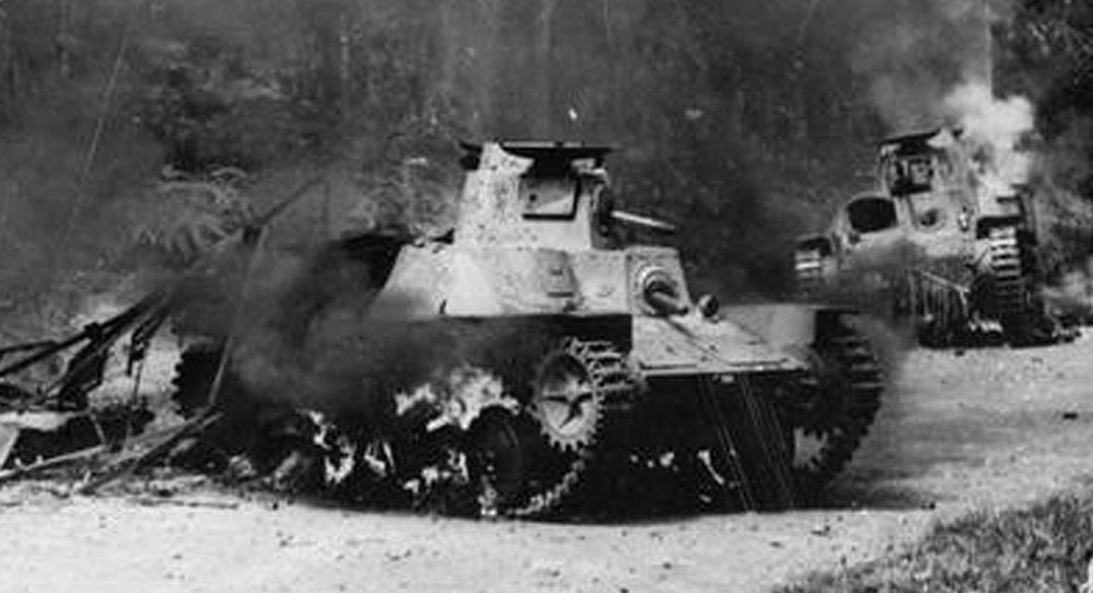 Two burning wrekcs of Japanese tanks sit smouldering on a jungle road near Singapore, crica 1942.