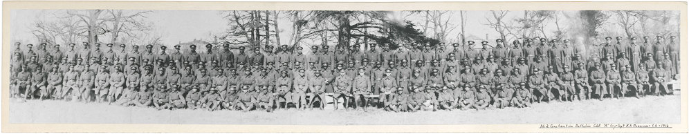 Men and officers of the No.2 Construction Battalion seated in three long rows on benches.