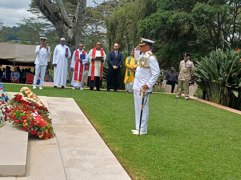 Indian Army Officer salutes the Stone of Remembrance at Nairobi War Cemetery as part of Remembrance Day 2025 Ceremonies. Many colorful flower wreaths have been laid at the base of the stone.