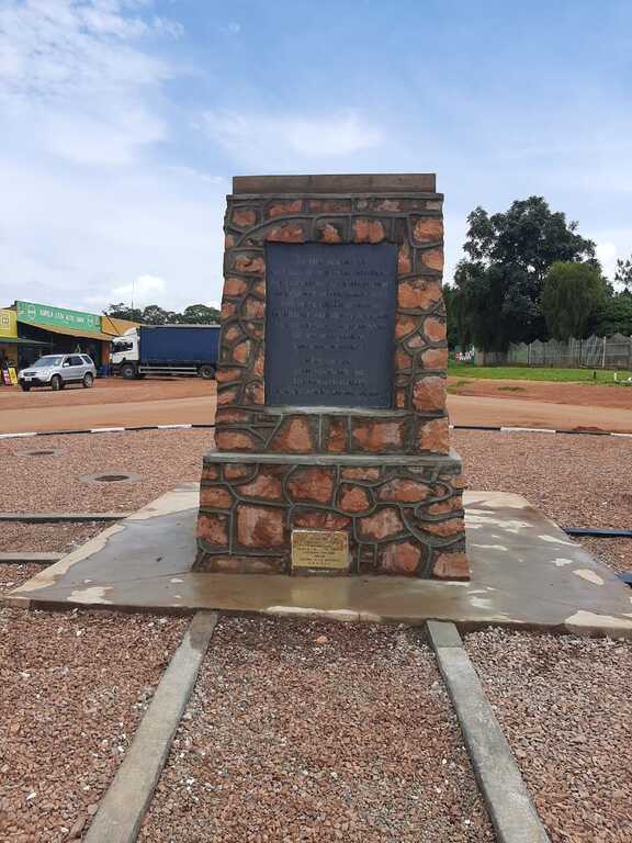 Red squat square column brickwork and central bronze plaque of the Mbala Memorial, Zambia