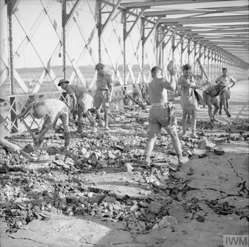 Royal Engineers sweeping up rubble on a bridge in Sicily in WW2.