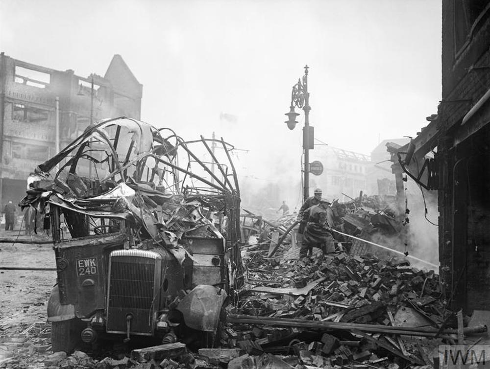 Smashed Bus Outside Coventry Station as firefighters tackle a blaze. Ruined buildings are visible in the background.
