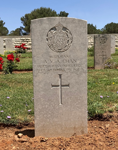 Headstone of Albert Chan showing cross, name, and engraved cap badge of the West Indies Regiment