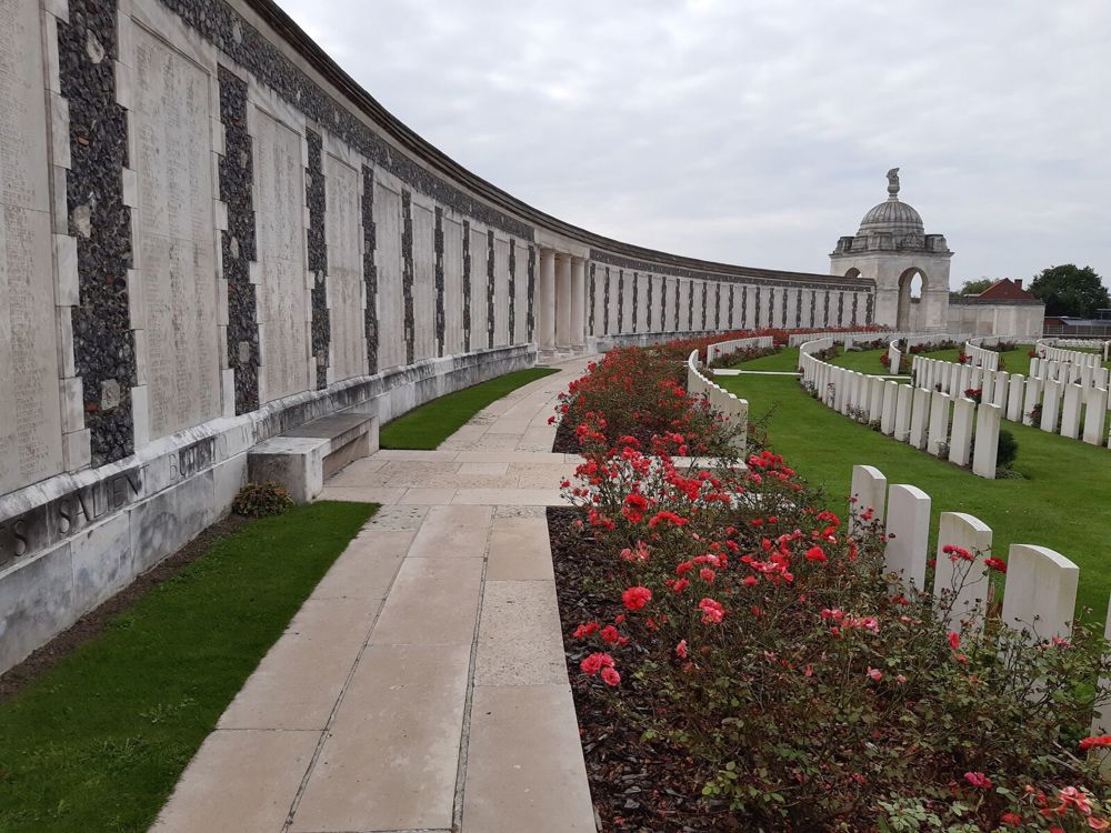 Tyne Cot Memorial with pedestrian footpath and rose bush planters visible in front of the memorial wall.