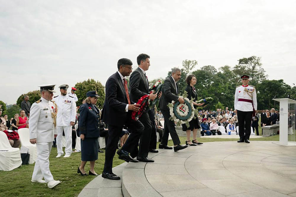 A variety of digniatires and military staff walking up the steps of the Singapore Memorial to lay wreaths during Remembrance Day 2025 services.