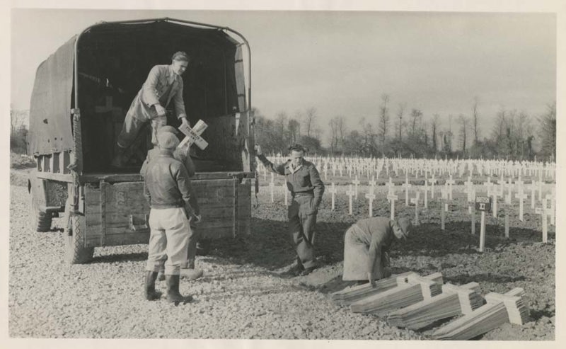 British Army Grave Concentration Unit stacking headstone crosses at the side of a drive in Bayeux War Cemetery