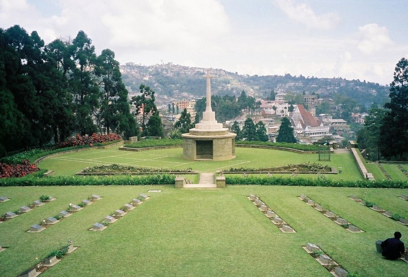 Kohima War Cemetery showing central Cross of Sacrifice and round shelter atop the outline of a tennis court.