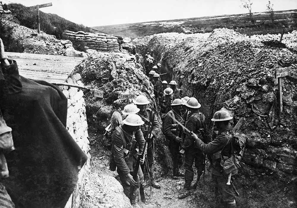 Men of the Lancashire Fusiliers forming up in a trench. Men at the front are inspecting their rifles. Each soldier is earing a tin helmet.