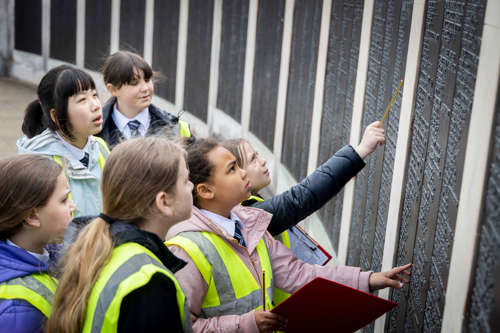 Schoolchildren looking at names on a war memorial
