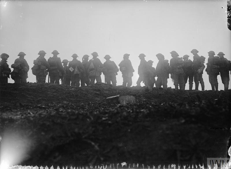 A long line of WW1 British infantry arrayed on a ridge during the Battle of the Somme. They are chatting and loosely arrayed.