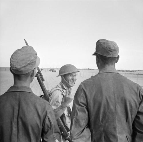 A British solider flashes the "V for Victory" sign at two German PoWs.