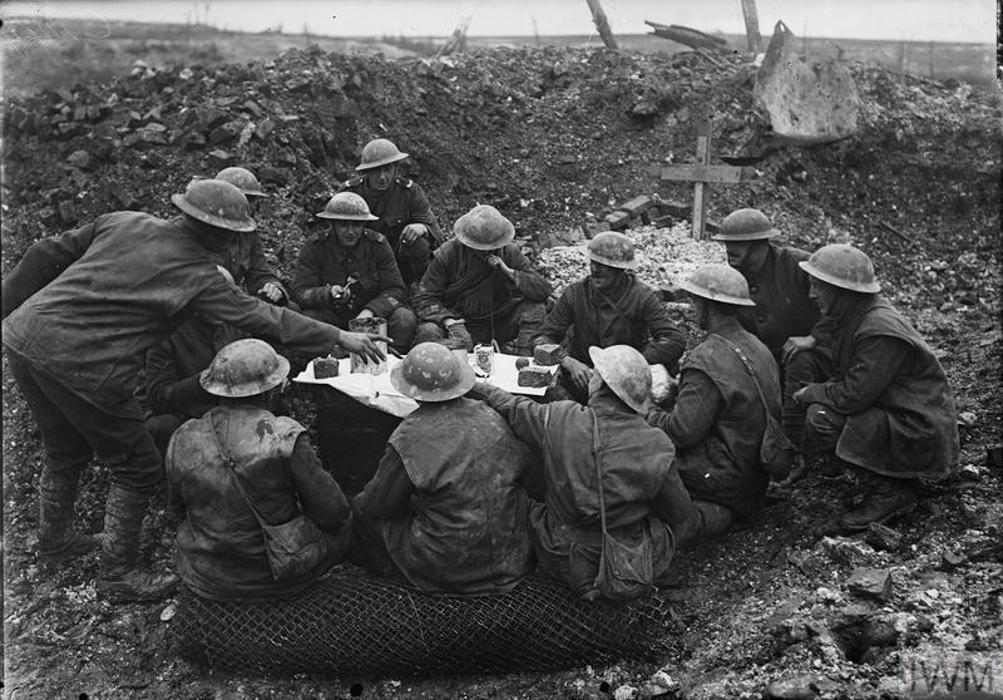 Soldiers eat Christmas dinner at a table set up in a shell crater, WW1.