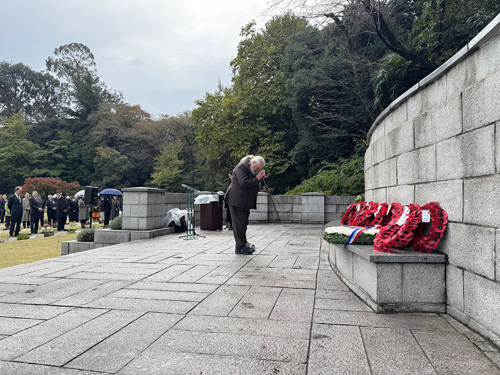 Indian diplomat bows before wreathes laid on a memorial at Yokohama War Cemetery.