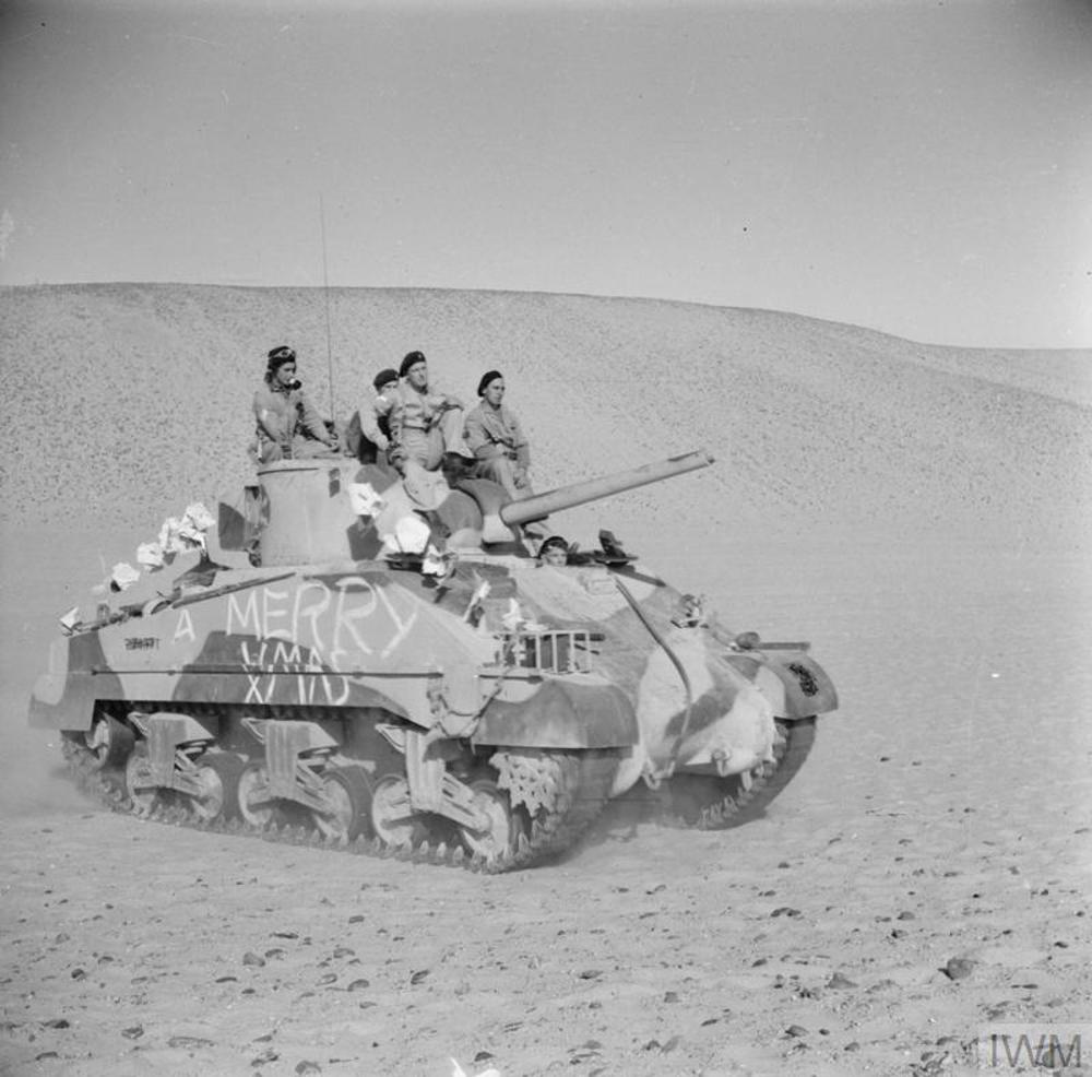 British soldiers riding their Sherman tank in North Africa circa 1942. The troops have decorated their tank with white Christmas decorations, including the slogan "A Merry Xmas".