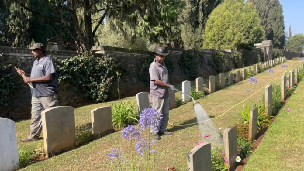 Gareners water borders and lawns alongside rows of headstones at Addis Ababa War Cemetery.