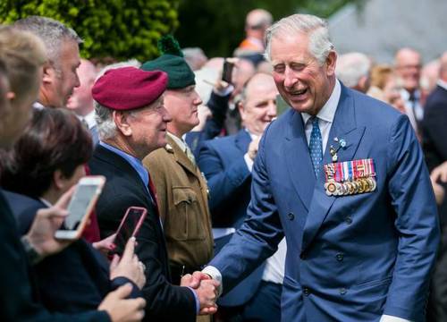 Prince Charles in a blue suit with medals pinned to his breast shakes hands with visitors to Ulster Tower.