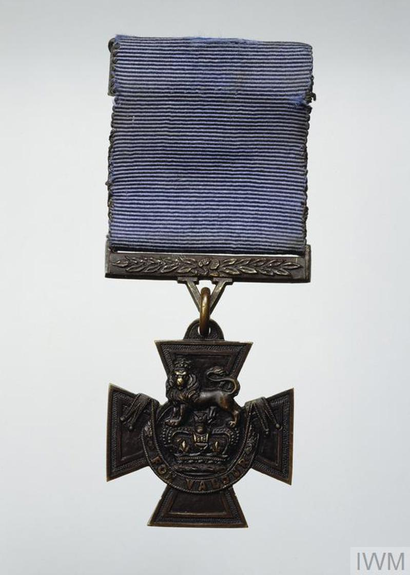 Bronze Victoria Cross in a Maltese Cross with faded blue ribbon.
