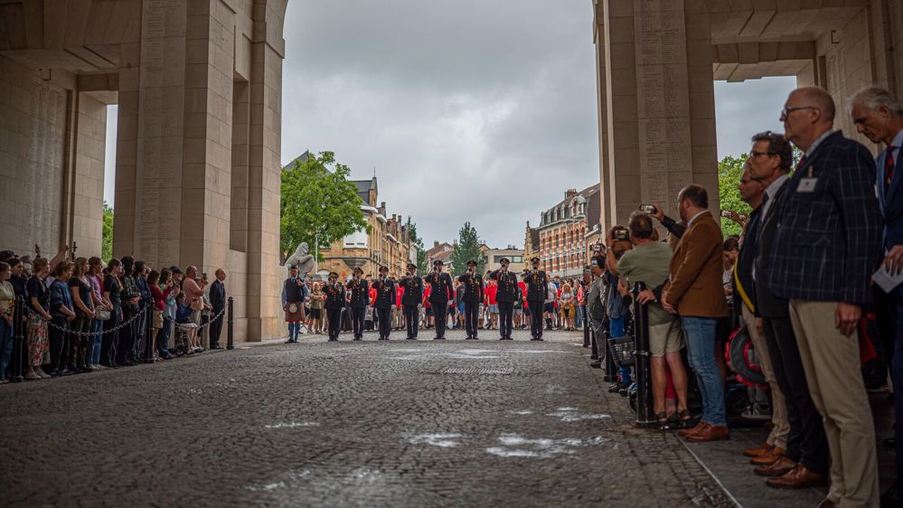 Buglers perform the last post beneath the arches of the Menin Gate while guests watch from both sides.