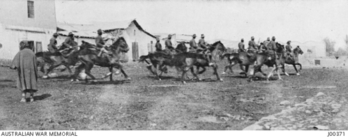 An action shot of Australian cavalrymen riding through the streets of Jericho.