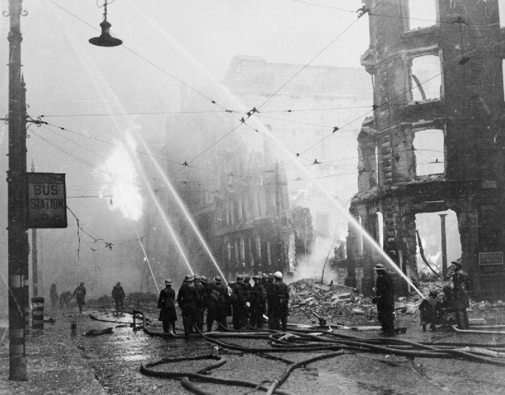 Firefighters shoot long jets of water from their houses tackling burning buildings in Manchester during the Manchester Blitz