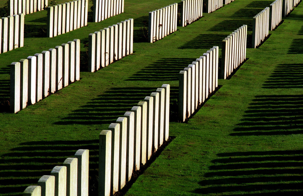Rows of headstones at Warlencourt British Cemetery casting long shadows on the neatly trimmed lawn.