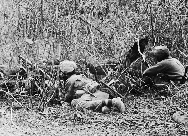 A pair of Sikh soldiers lie in thick scrub while on sentry duties.