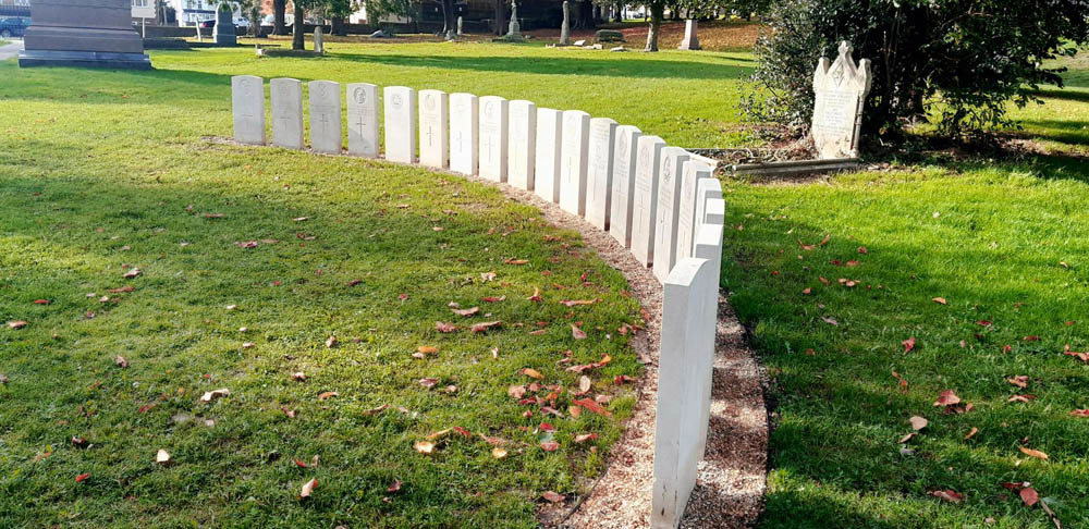 Row of CWGC Headstones arranged in a curved ark in a Kent park.