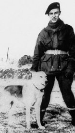 Paratrooper Emile Corteil in jacket and beret poses with his dog Glen.