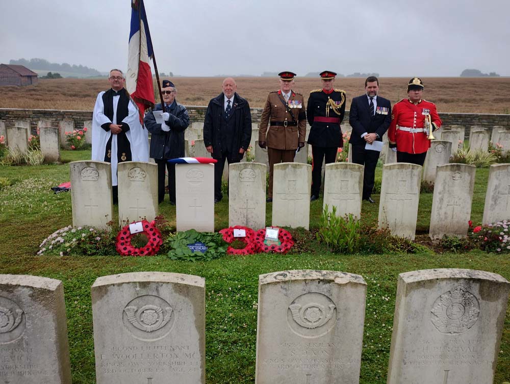 The military party stand behind the headstone of L/Cpl Dowding