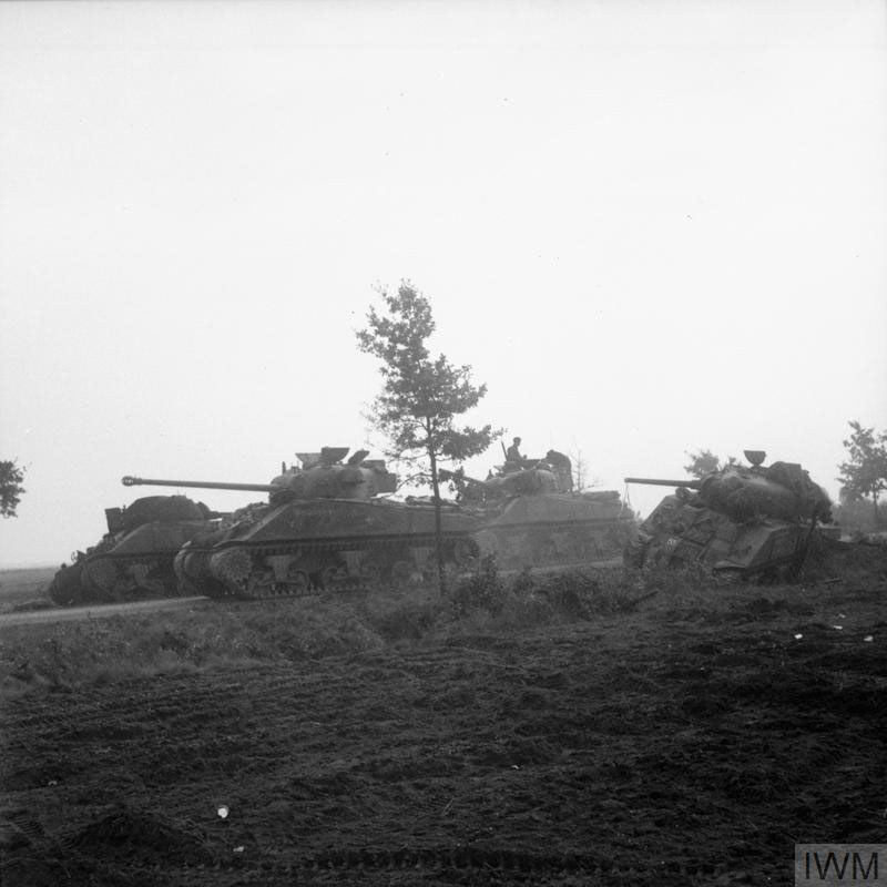 British Tanks of XXX Corps moving up a road flanked by a muddy field and some trees in Holland during Operation Market Garden.