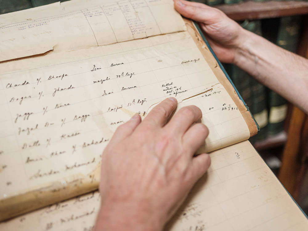 Close up of a person's hands holding and inspecting old handwritten yellowed documents.