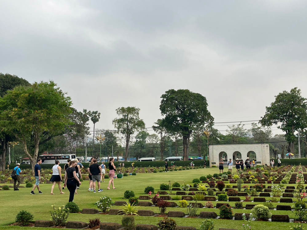 Visitors walking through Kanchanaburi War Cemetery