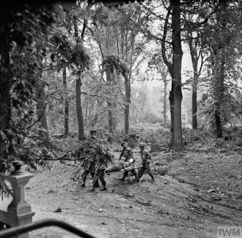 British paratroopers carry a wounded comrade on a stretcher through Arnhem's woods to an aid post.