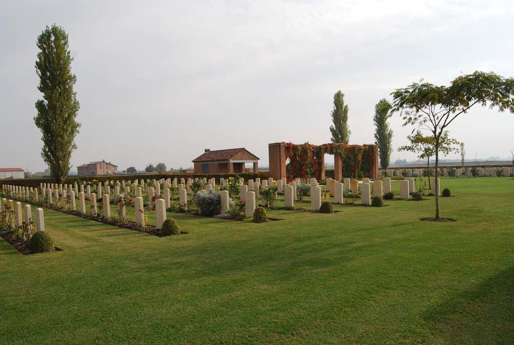 Wide view of Argenta Gap War Cemetery with Roman-inspired shelter visible in the background.